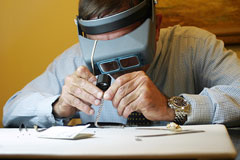 a jeweler, wearing a binocular headband magnifier, examines bracelet diamonds