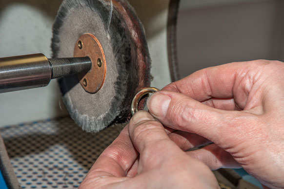 jeweler buffing a golf ring on a buffing machine